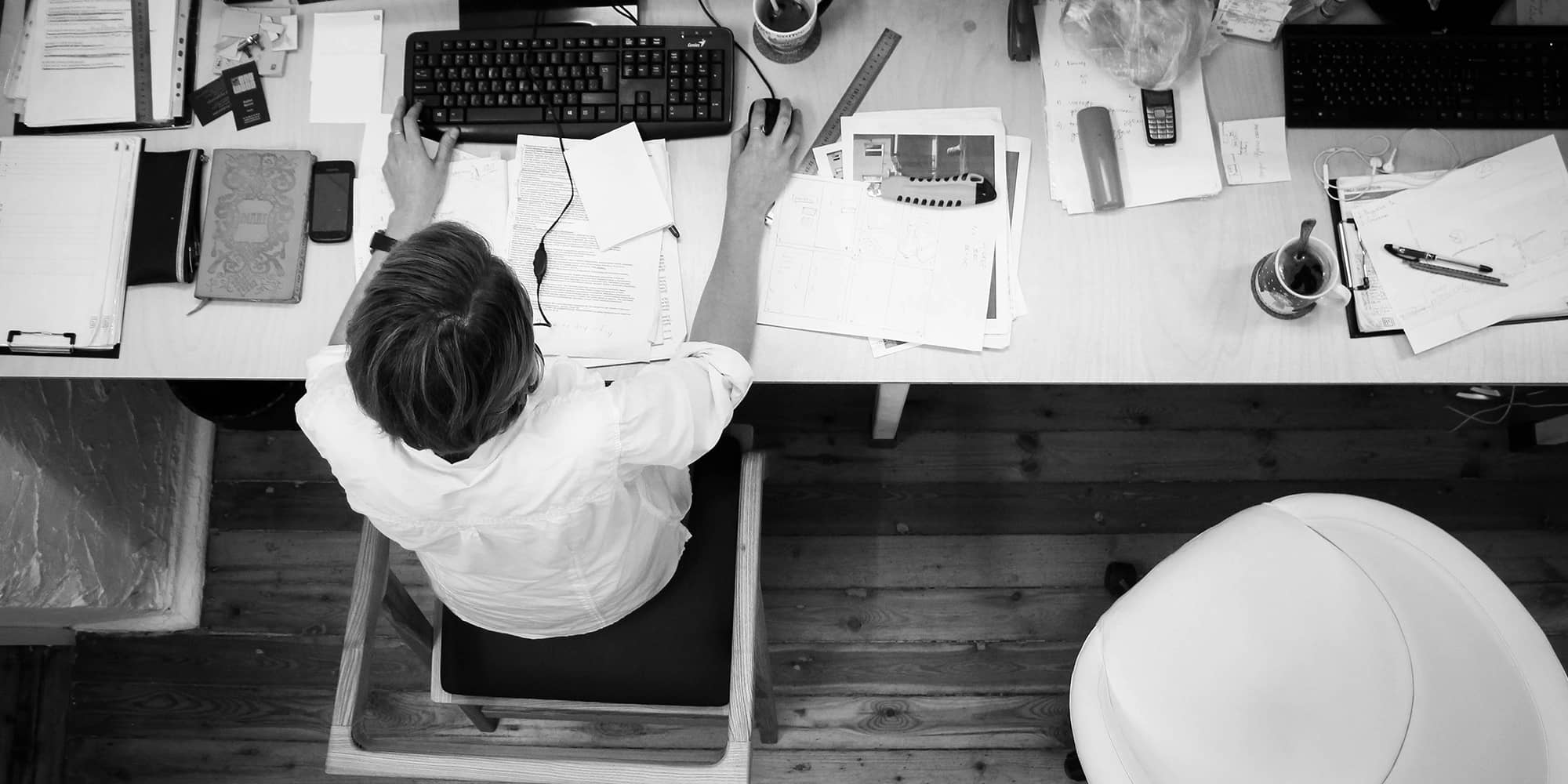 Vue en plongée d’une personne travaillant à un bureau, symbolisant l’occupation temporaire d’un local professionnel