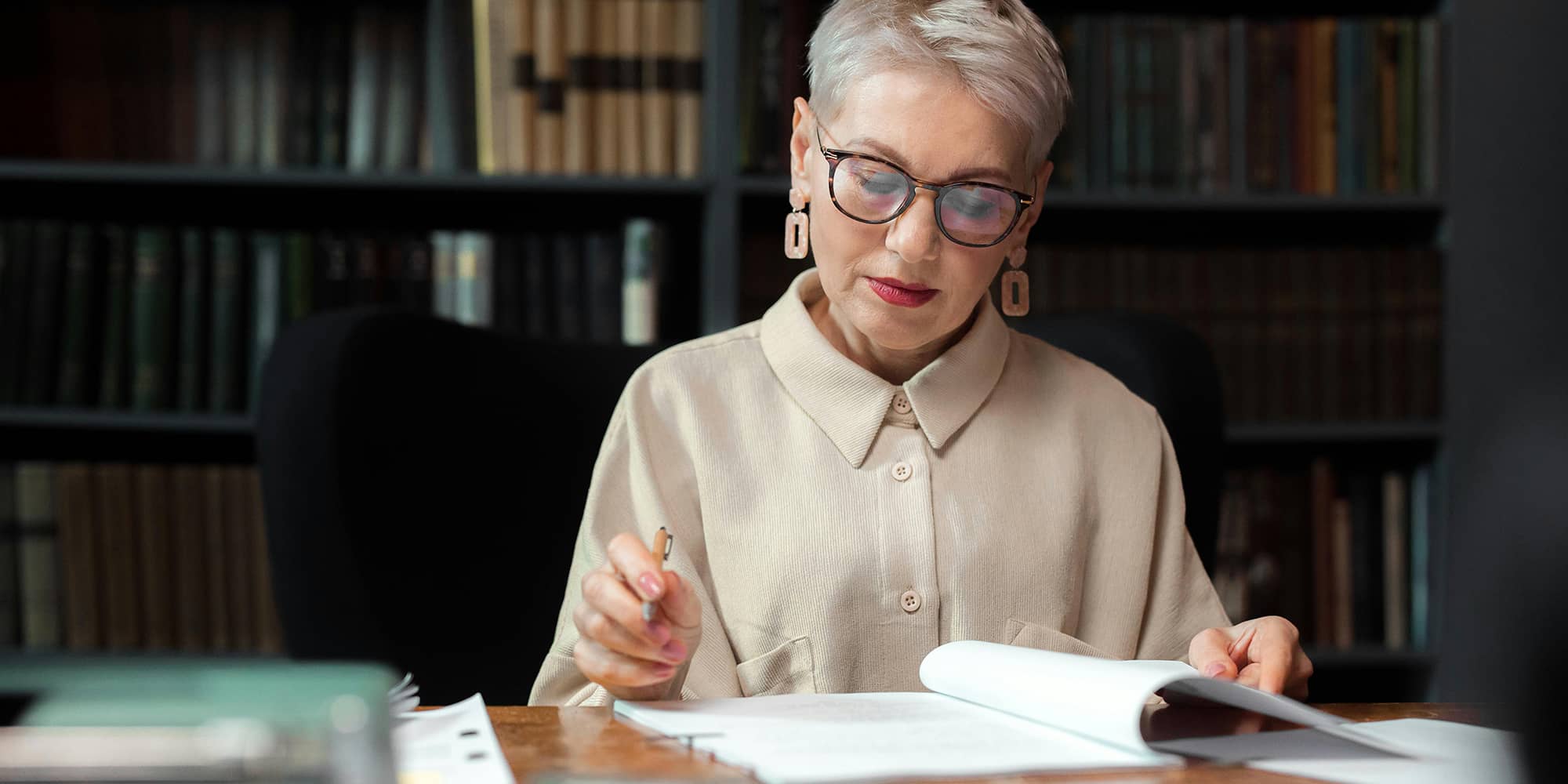 Avocate analysant un dossier de marque dans une bibliothèque juridique, illustrant la procédure d’opposition à l’INPI en droit de la propriété intellectuelle