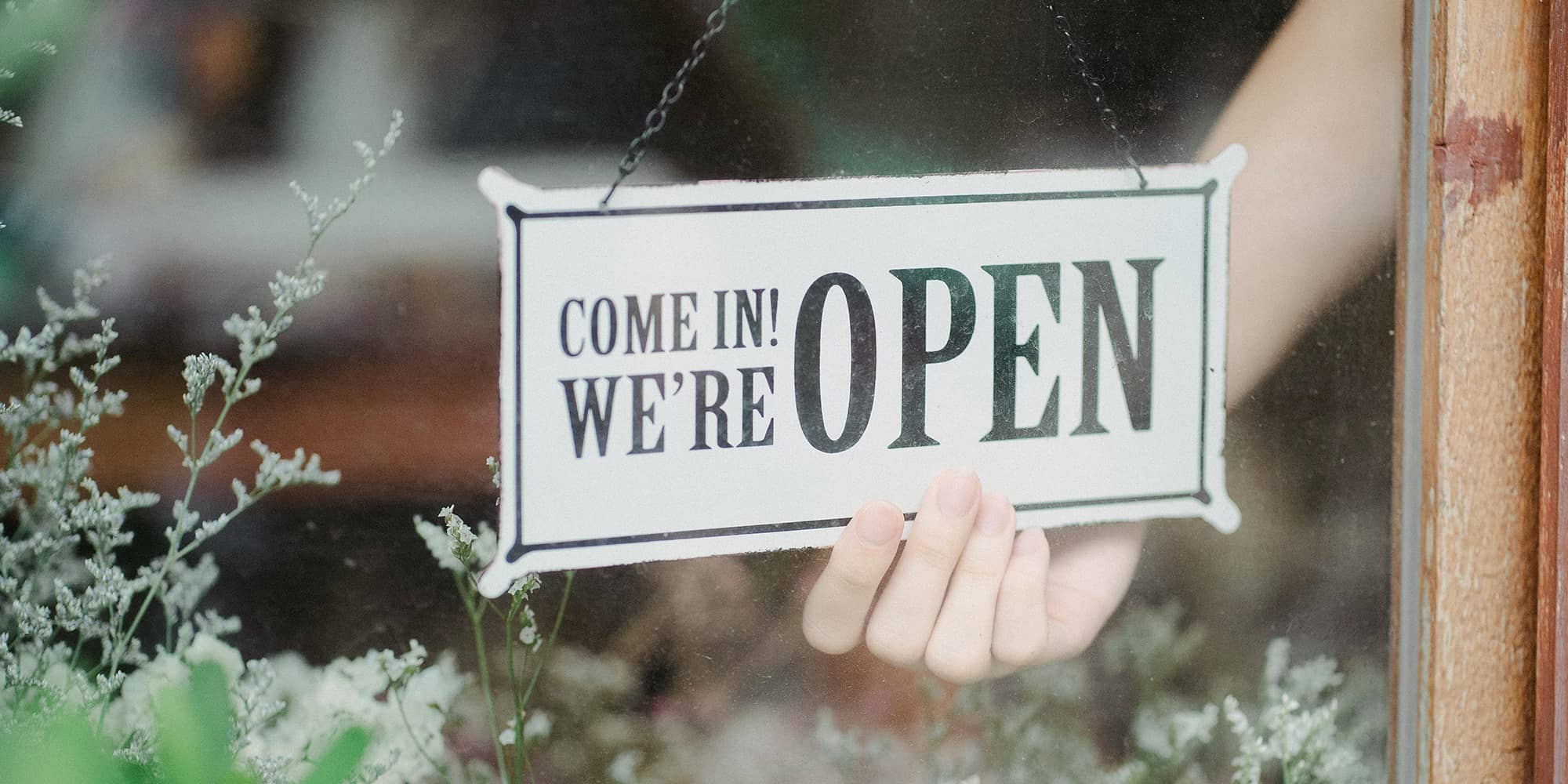 Panneau « OPEN » accroché à la vitrine d’un commerce, illustrant l’ouverture d’un local commercial et les enjeux de révision du loyer lors du renouvellement d’un bail commercial