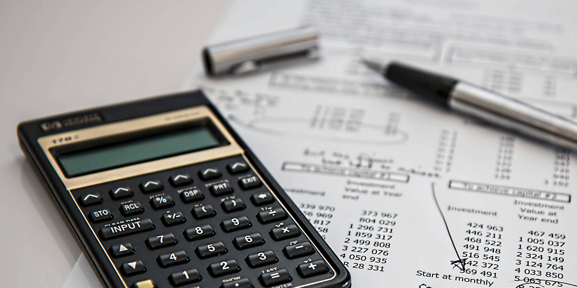 Calculatrice posée sur des documents financiers, symbolisant l’organisation, la gestion et la sécurisation des flux de trésorerie au sein d’un groupe de sociétés